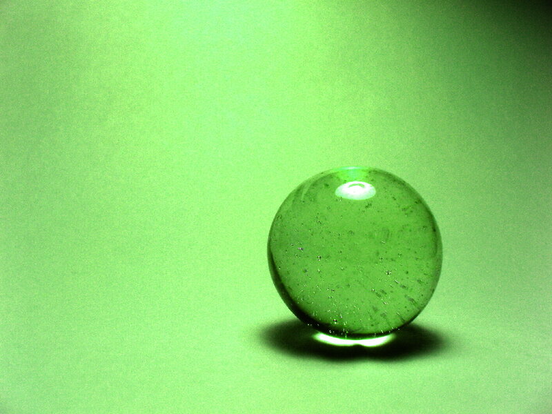 Green glass marble on green surface
