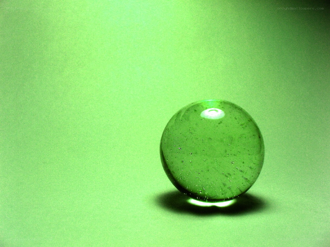 Green glass marble on green surface