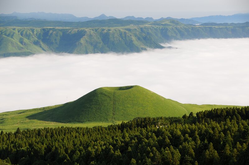 Green hill above sea of clouds