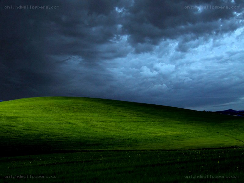 Green hill under stormy sky