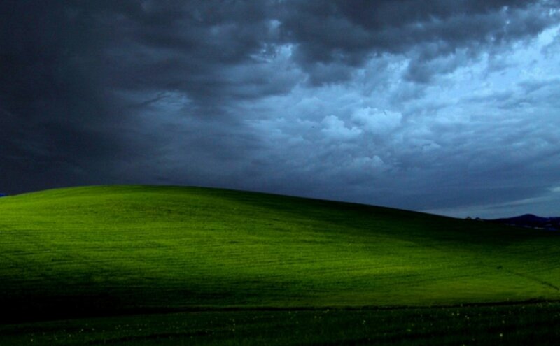 Green hill under stormy sky