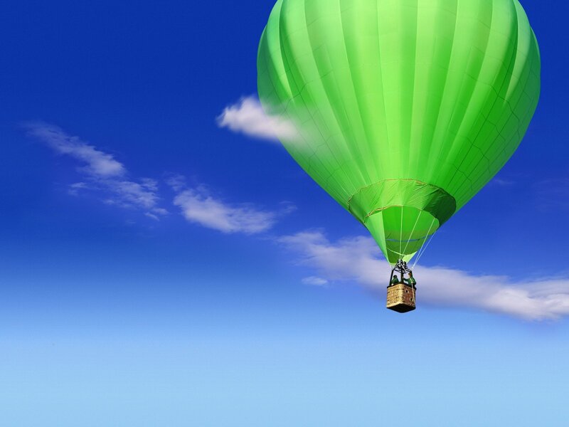Green hot air balloon in blue sky