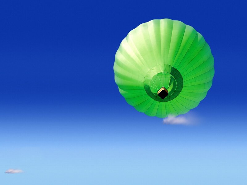 Green hot air balloon in blue sky