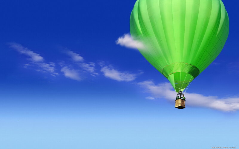 Green hot air balloon in blue sky