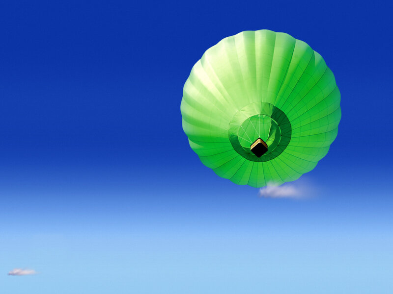 Green hot air balloon in blue sky