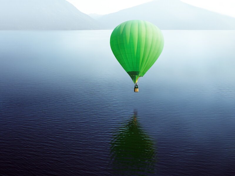 Green hot air balloon over lake