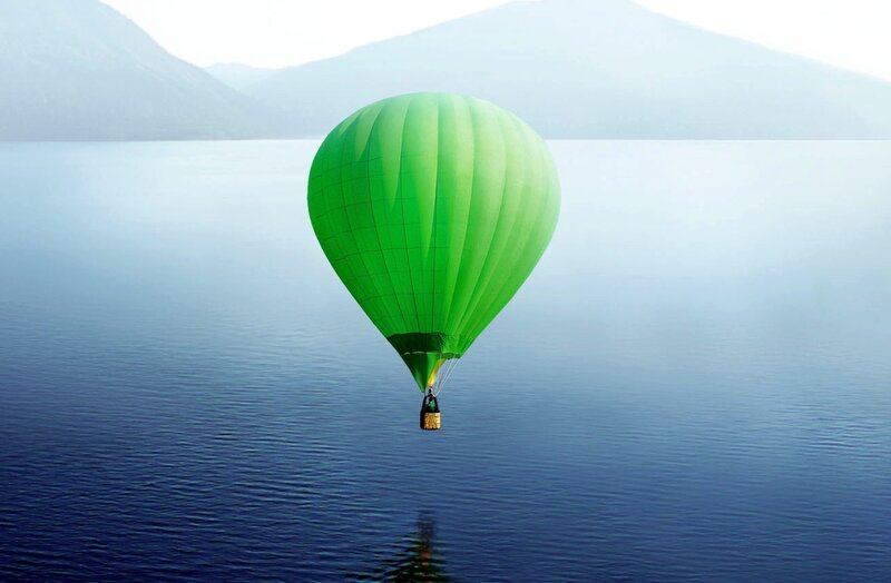 Green hot air balloon over lake