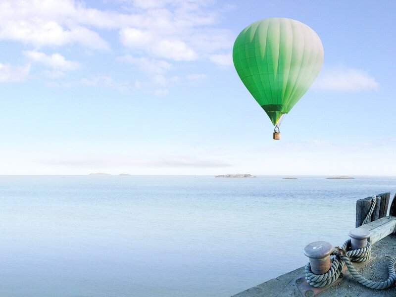 Green hot air balloon over sea