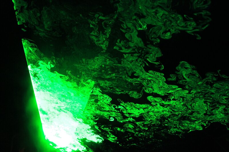 green liquid swirling in darkness
