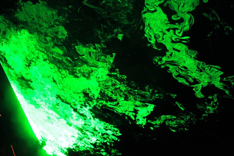 green liquid swirls in darkness