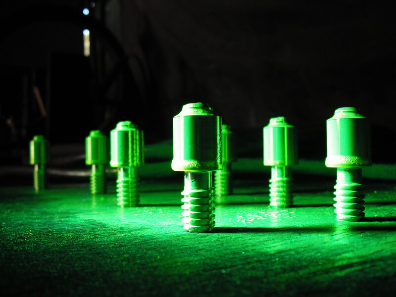 Green-lit metal bolts on a surface