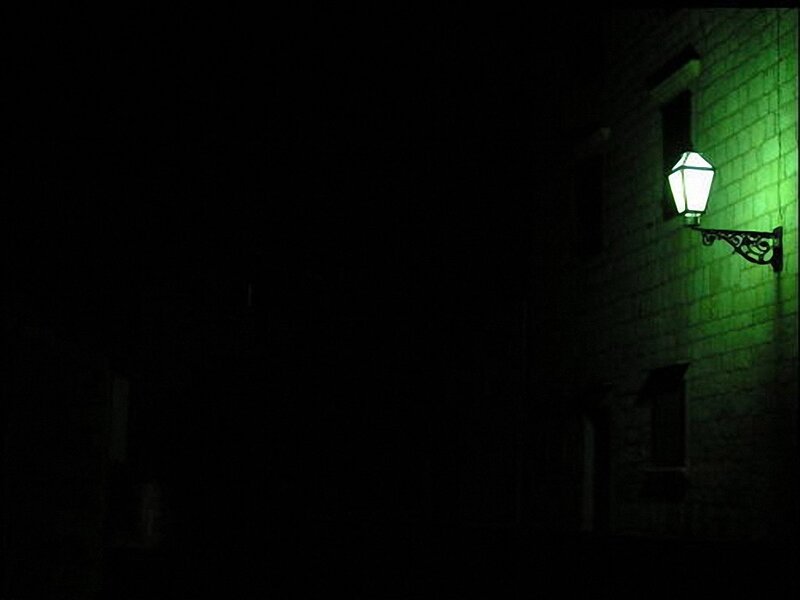 green-lit street lamp at night