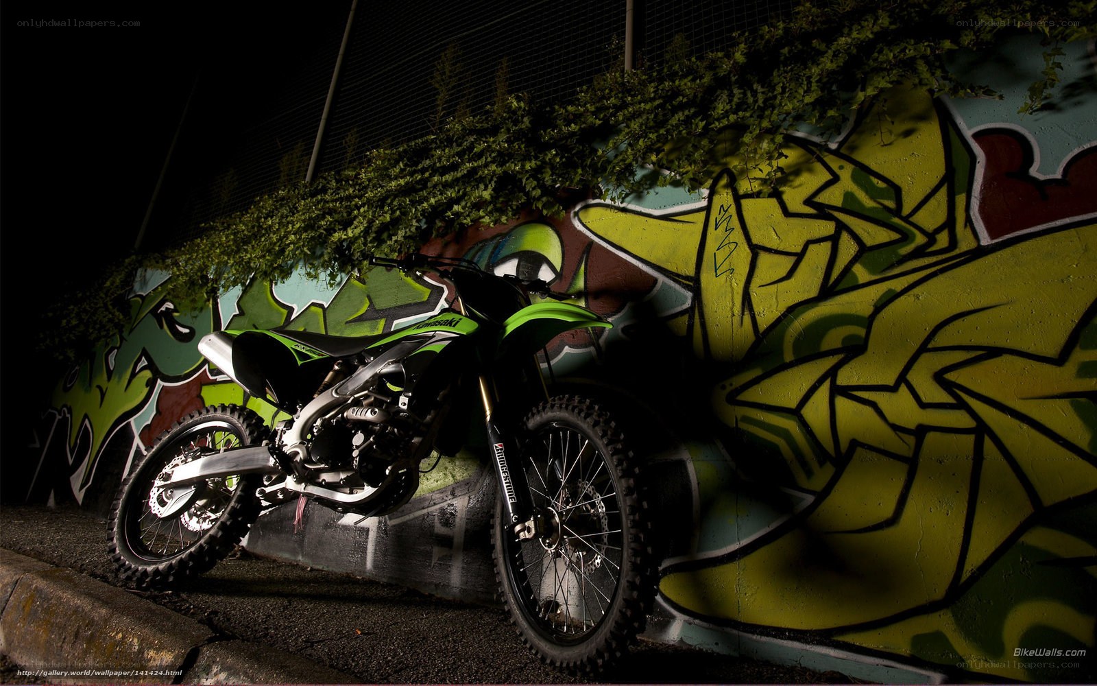 green motorcycle against graffiti wall