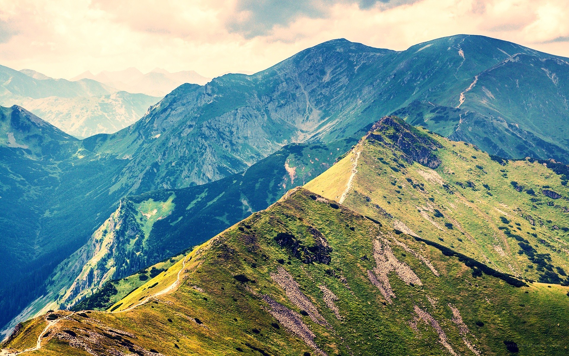 Green mountain peaks under cloudy sky