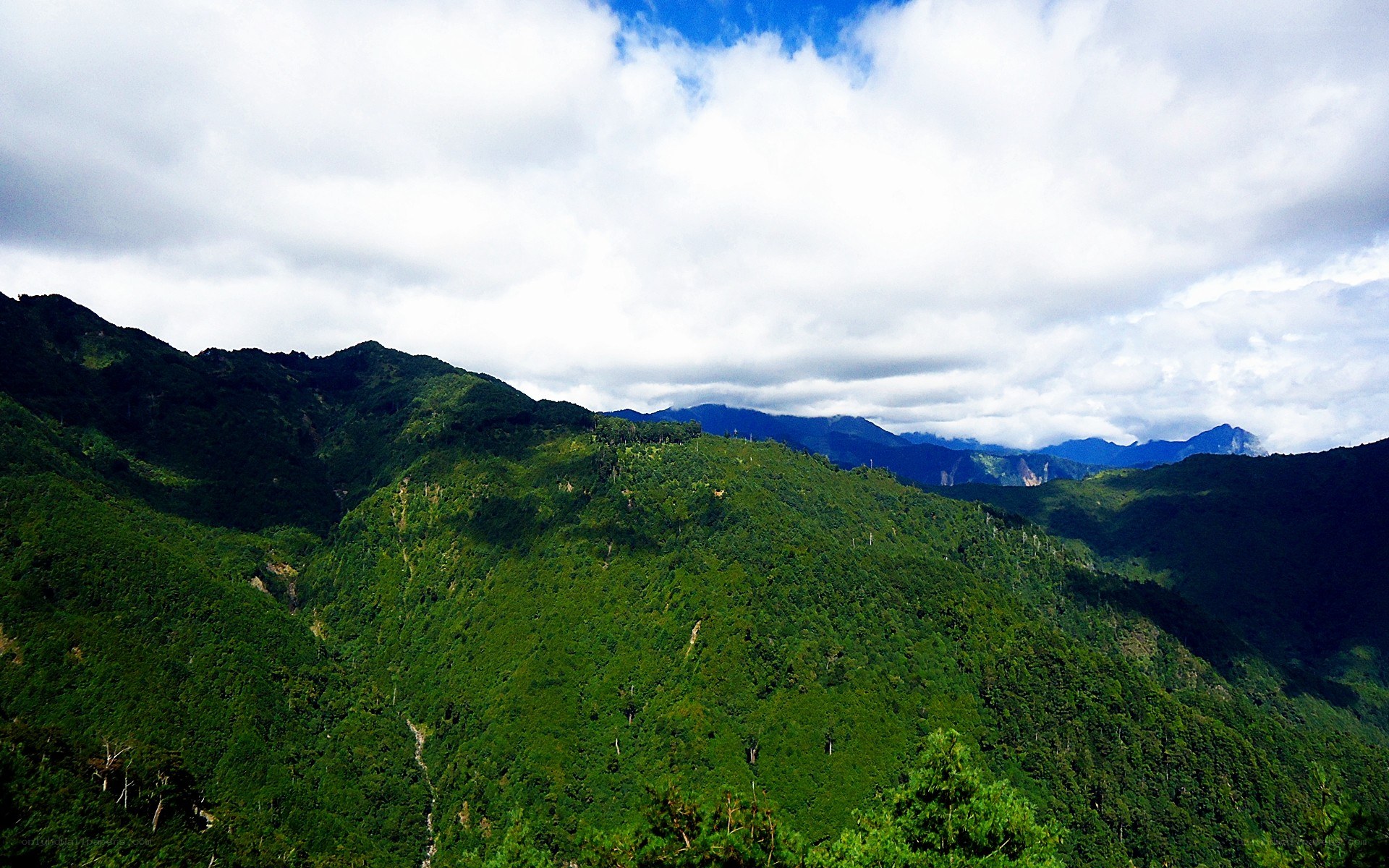 Green mountains under cloudy sky