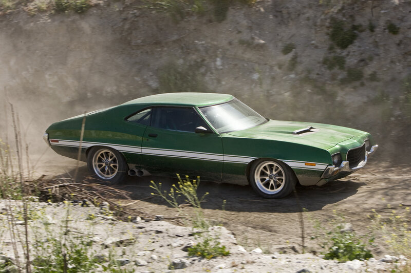 Green muscle car on dirt road