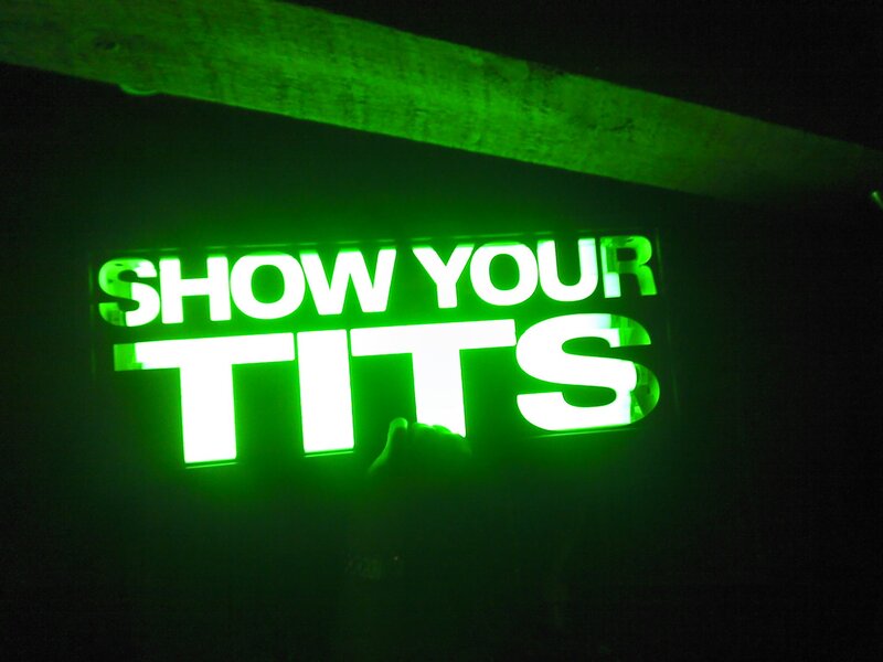 green neon sign reading show your tits