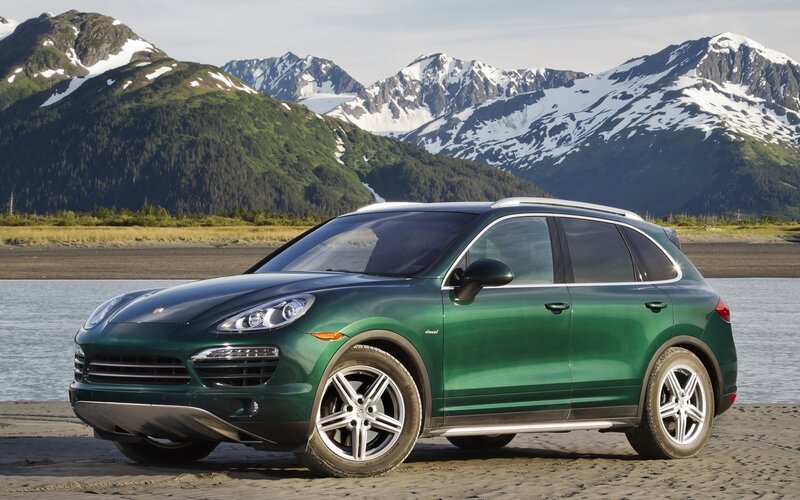Green Porsche Cayenne in mountain landscape