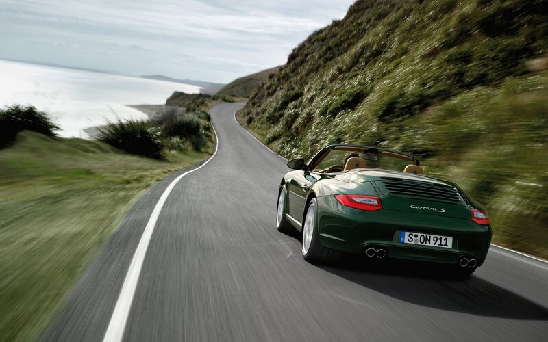 Green Porsche convertible on coastal road