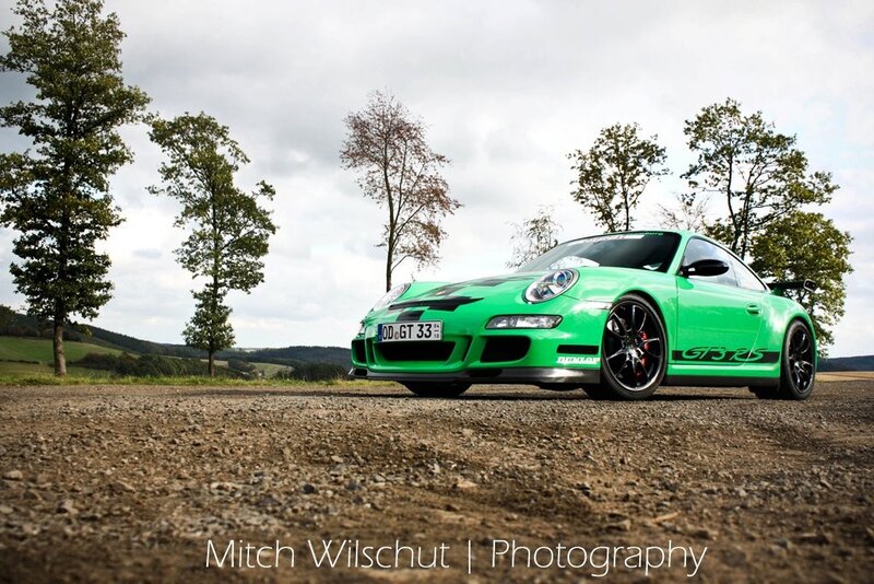 Green Porsche on a gravel road