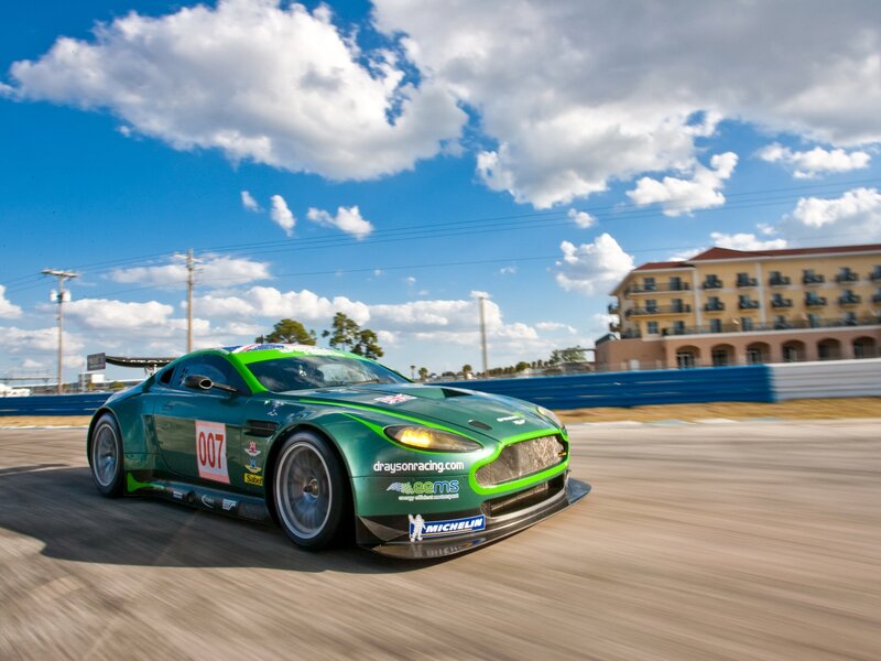 Green Race Car — Dynamic, Afternoon, Photograph, Race Track, Building, Clouds