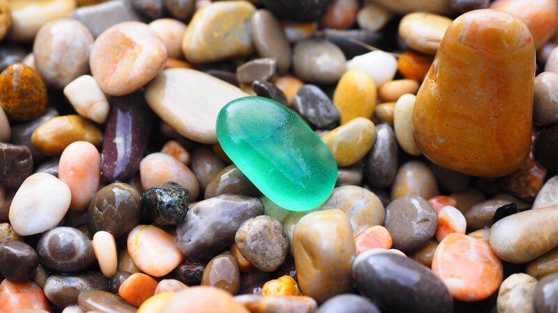 Green sea glass among pebbles