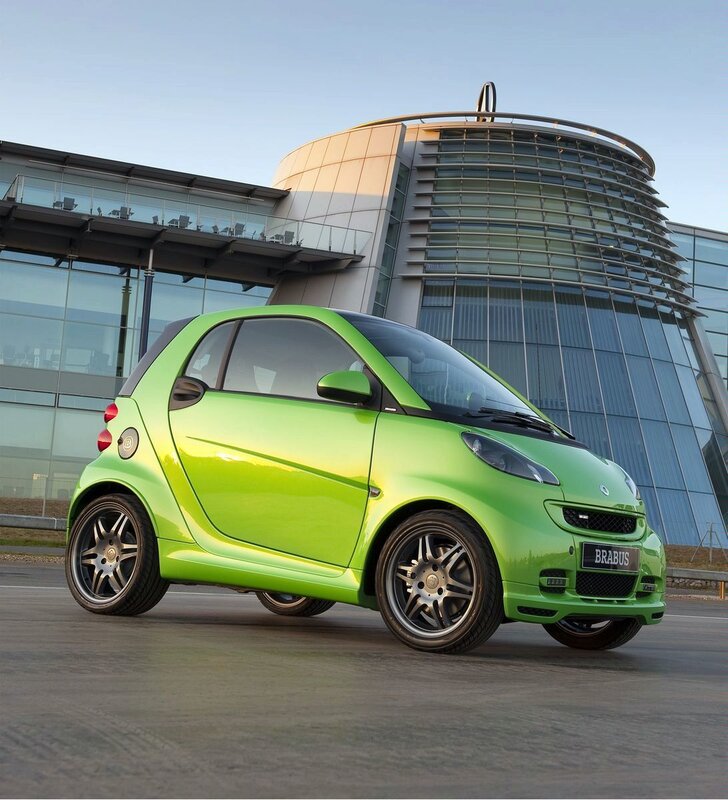 Green smart car in front of building