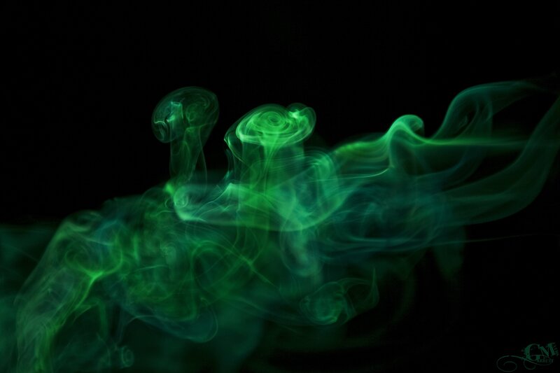 Green smoke swirls in darkness