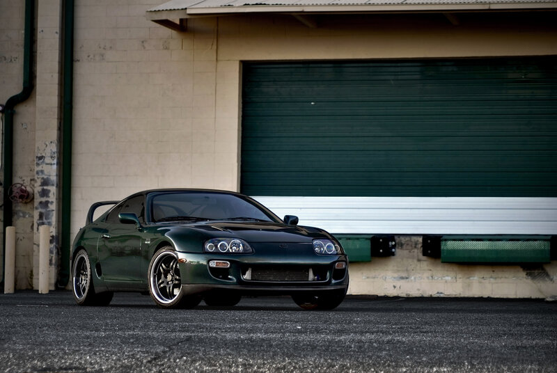 Green sports car in front of garage