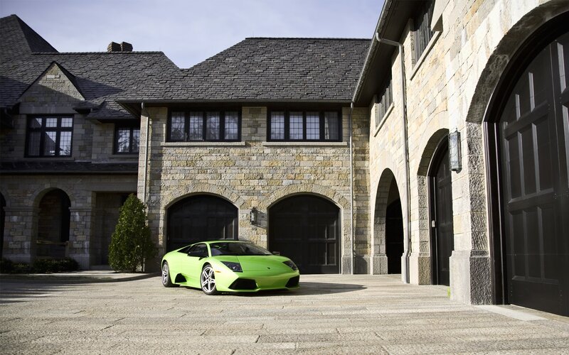 Green sports car in front of stone house
