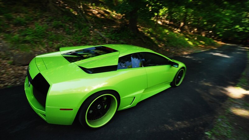 Green sports car on forest road