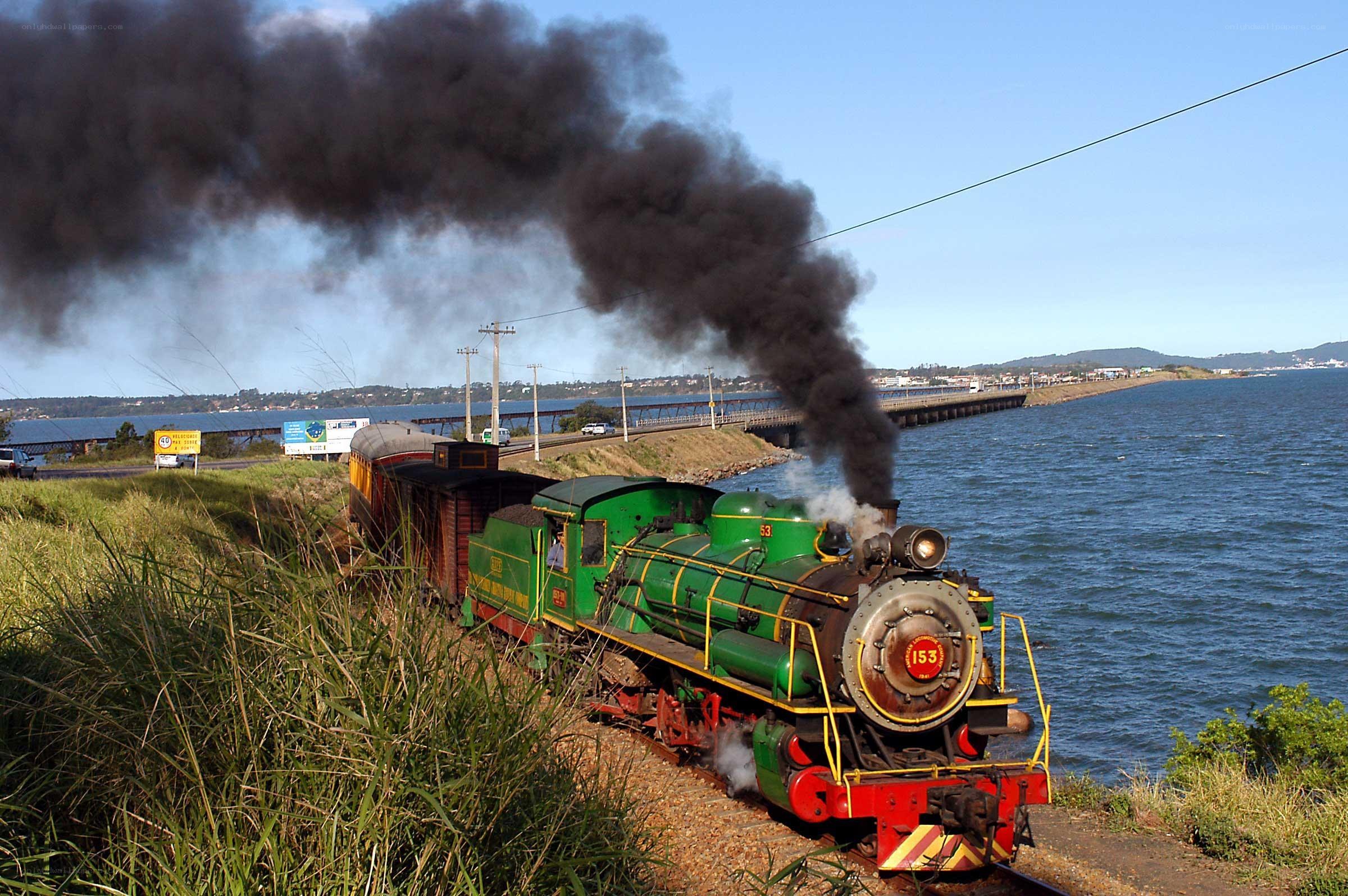 Green steam train by the water