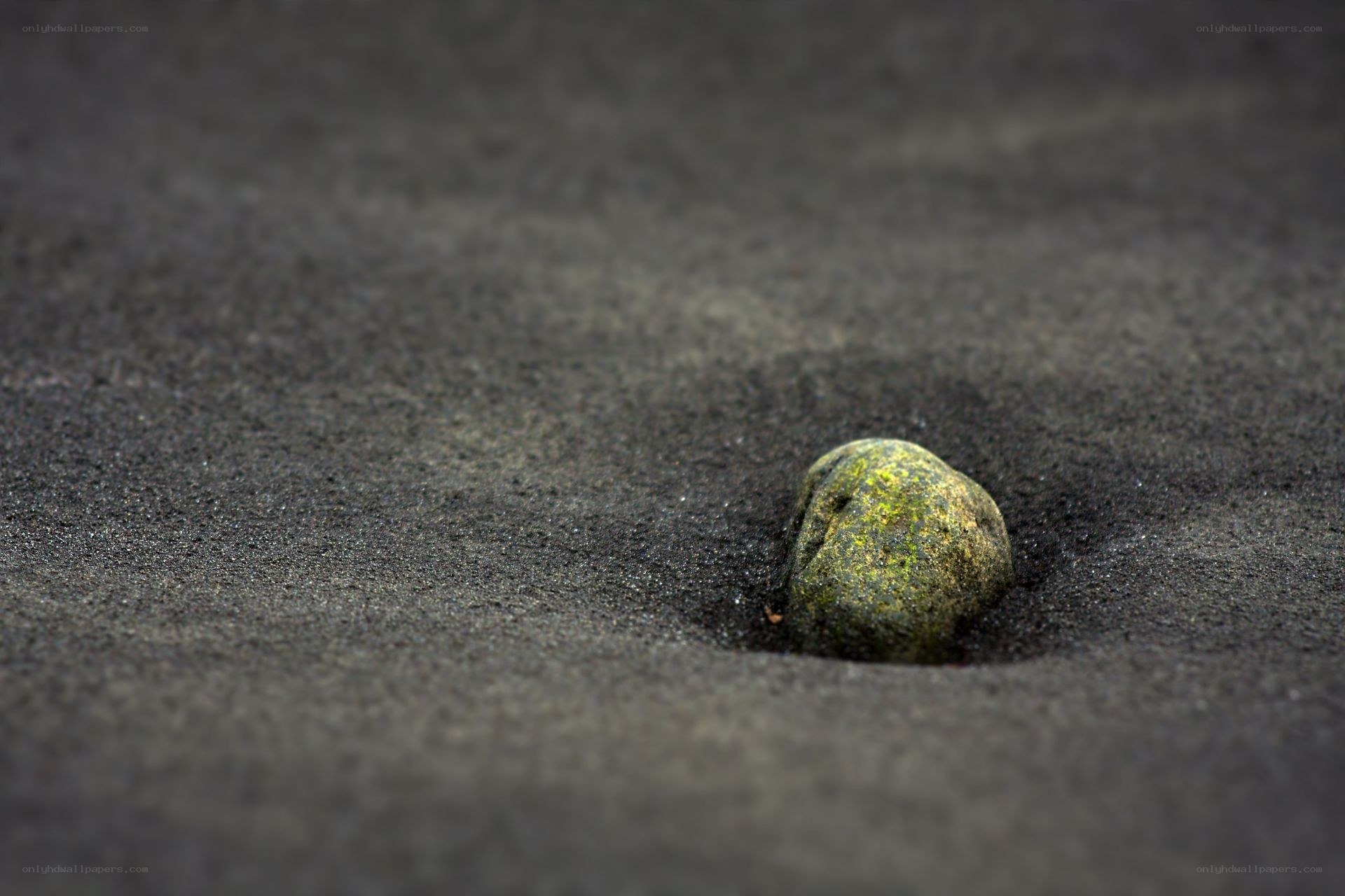 green stone in black sand