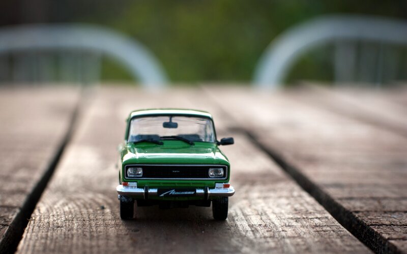 Green toy car on wooden planks