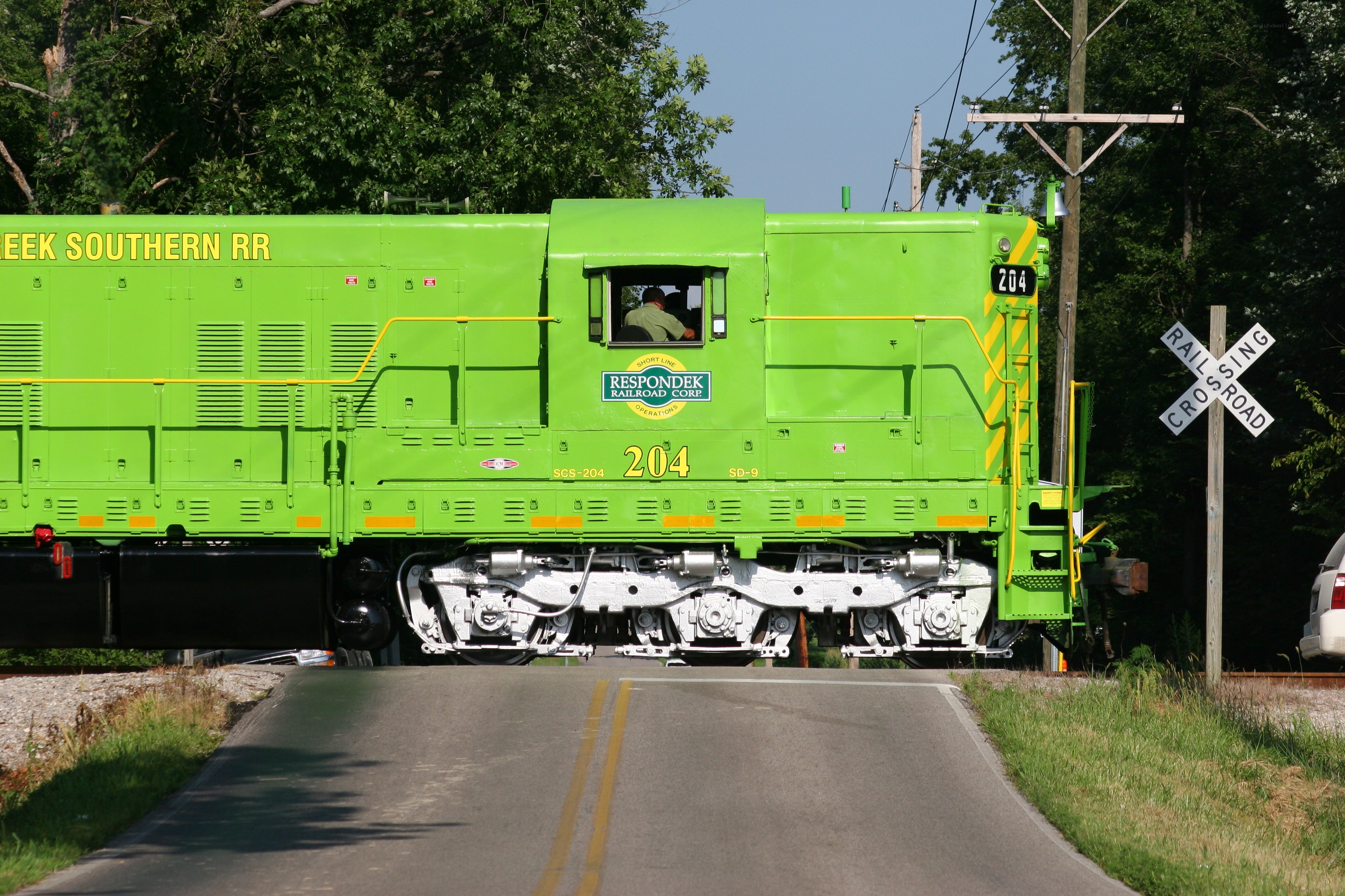 Green train at railroad crossing
