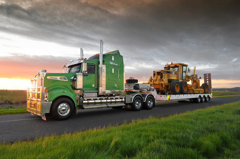 Green truck hauling construction equipment