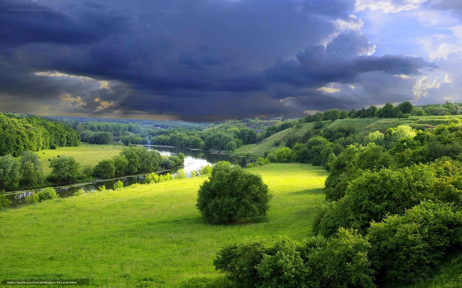 Green valley with river under stormy sky