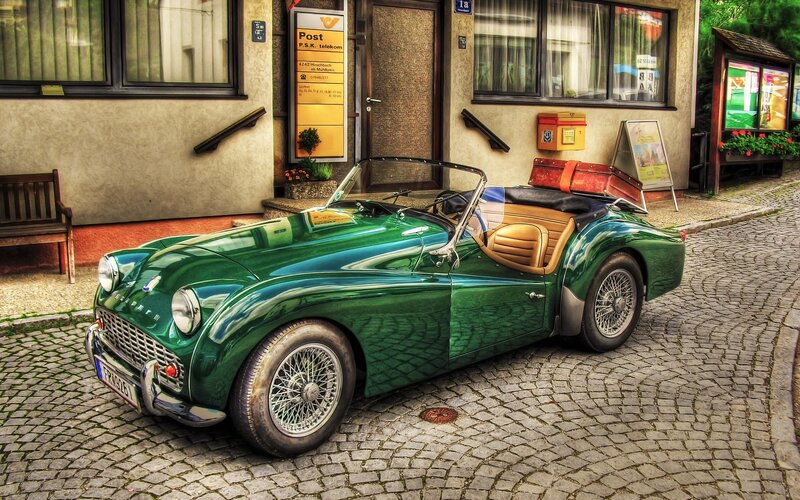 Green vintage car on cobblestone street