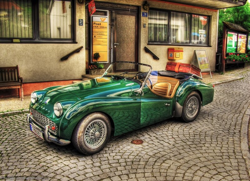 Green vintage car on cobblestone street