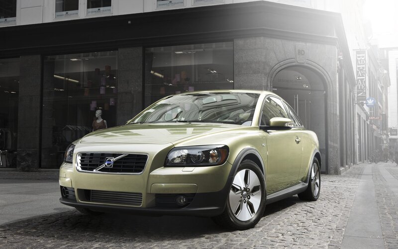 green volvo c30 parked on cobblestone