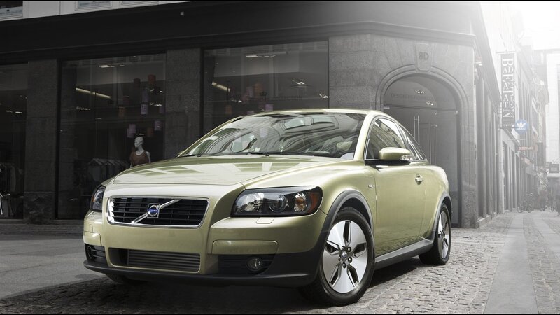 Green Volvo C30 parked on cobblestone