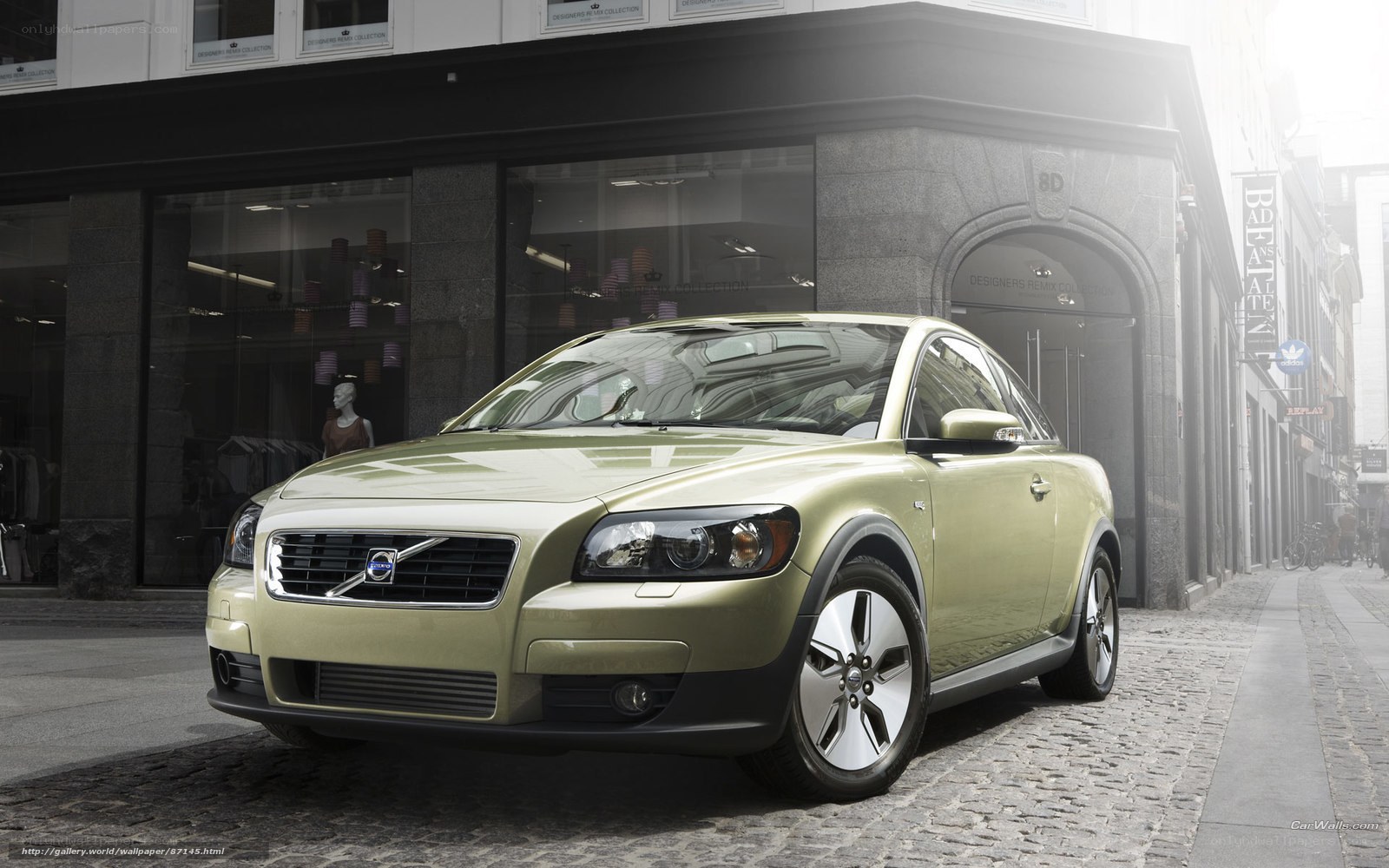 green volvo c30 parked on cobblestone