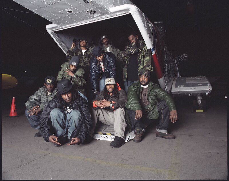 Group of rappers posing by a plane