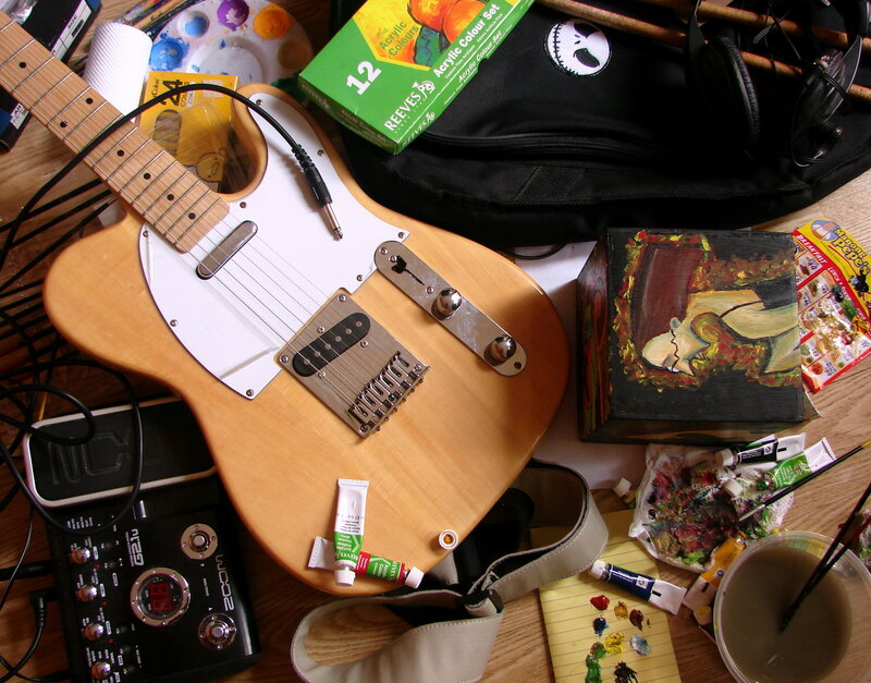 Guitar and art supplies on table