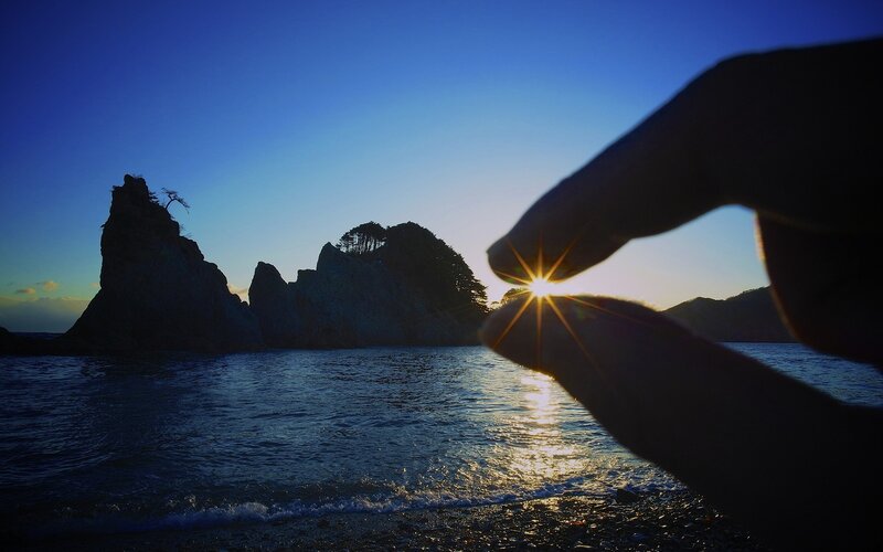 Hand framing the setting sun