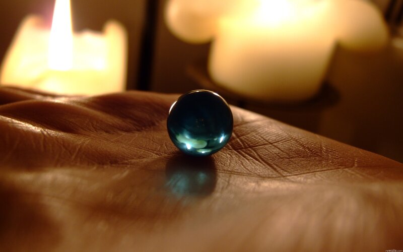 Hand holding a blue glass marble