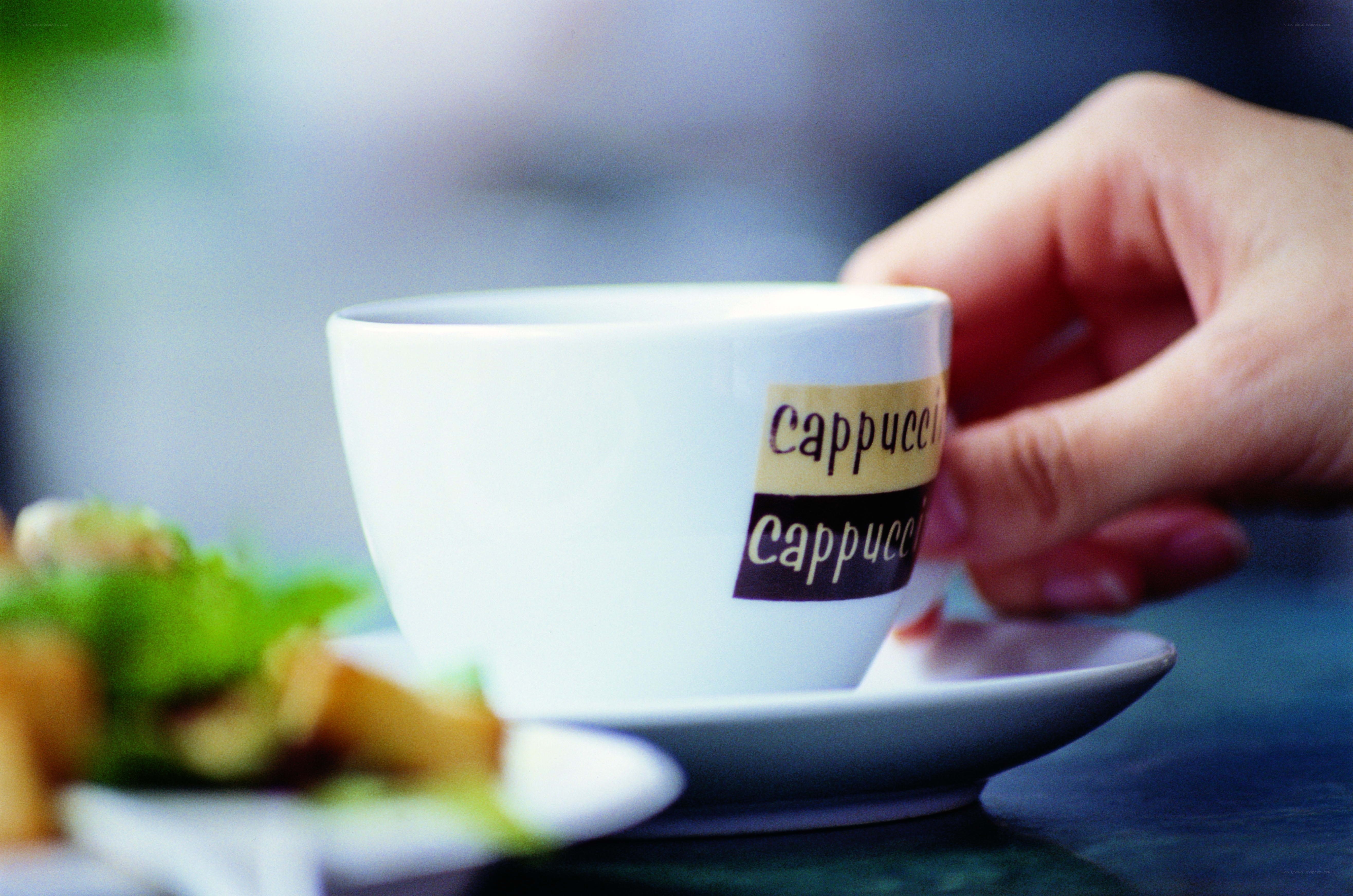 Hand holding a cappuccino cup