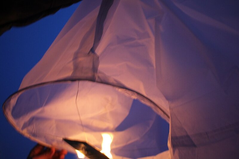 Hand holding a lit sky lantern