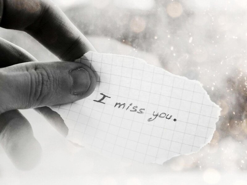 Hand holding a note saying 'I miss you'
