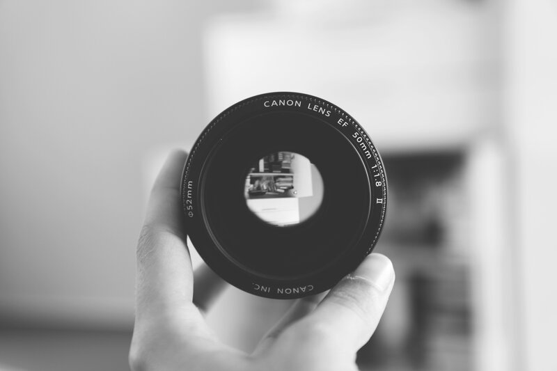Hand Holding Camera Lens — Black, Neutral